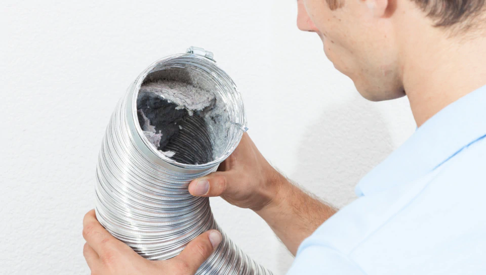 worker holding dryer vent tube full of dirt